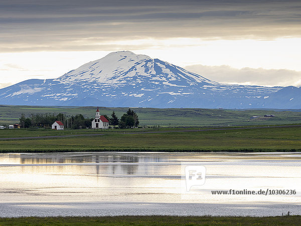 A traditional church on a lake shore in a mountain landscape.