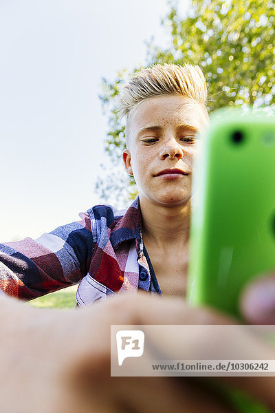 Teenager-Junge sucht auf Smartphone im Freien