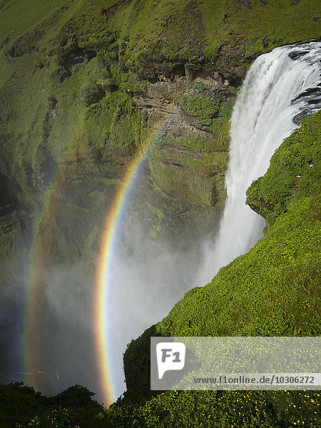 Wasserfall Skogafoss mit einem doppelten Regenbogen im Nebel und Dampf  der aus dem Wasser aufsteigt.