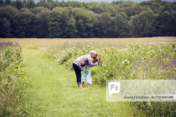 A mature woman and a young girl in a wildflower meadow.