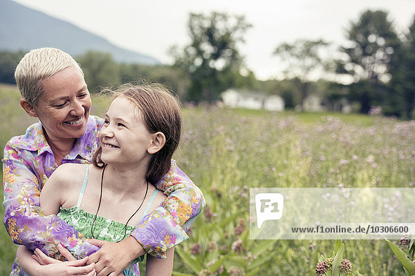 A mature woman and a young girl in a wildflower meadow.