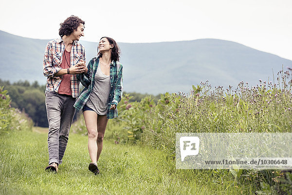 A couple  man and woman walking through a meadow in the countryside.