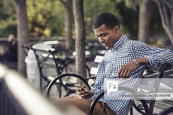Ein Mann in einem Park  der ein Smartphone ansieht