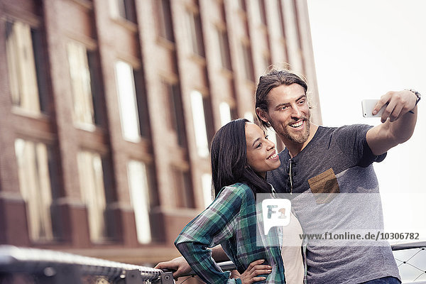 A couple  man and woman taking a selfie by a large building in the city