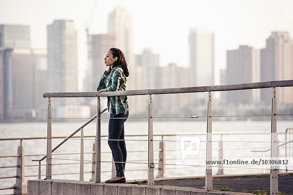 Eine Frau steht am Wasser  Blick auf die Stadt über dem Wasser in New York City.