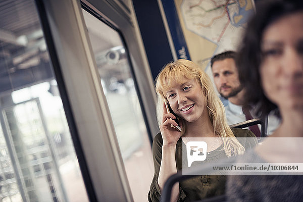 Eine blonde Frau in einem Stadtbus  die mit ihrem Smartphone telefoniert