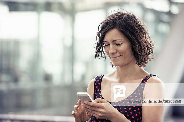 Eine Frau auf der Straße  die ihr Handy benutzt  um nach Nachrichten zu suchen