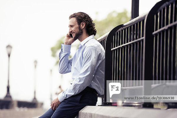 Ein Mann sitzt auf einer Stufe auf der Straße und telefoniert.