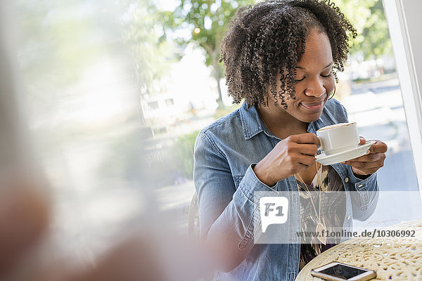 A woman holding a coffee cup at a coffee shop.