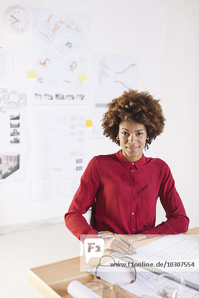 Porträt einer lächelnden jungen Architektin am Schreibtisch