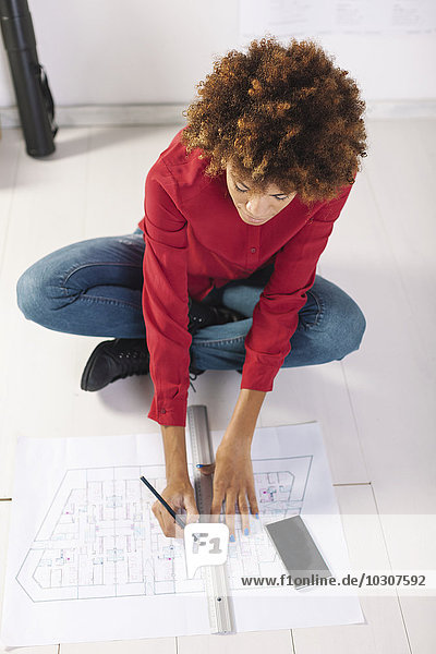 Young female architect working on the floor of her office