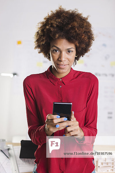 Portrait of young female afro architect with smartphone at her office