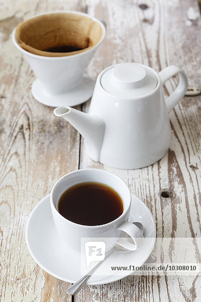 Tasse schwarzer Filterkaffee und Kaffeekanne auf Holz