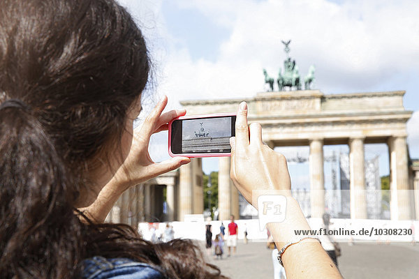 Deutschland  Berlin  Touristinnen fotografieren Brandenburger Tor mit Smartphone