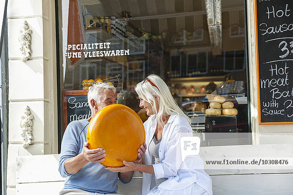 Niederlande  Amsterdam  Seniorenpaar auf der Bank sitzend mit Käsebrot