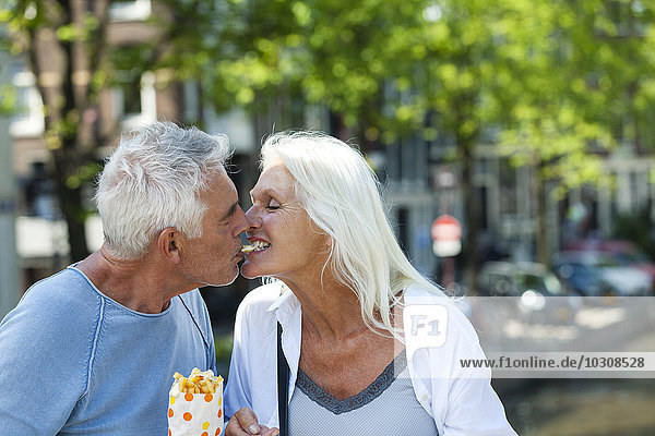 Netherlands  Amsterdam  happy senior couple sharing French Fries