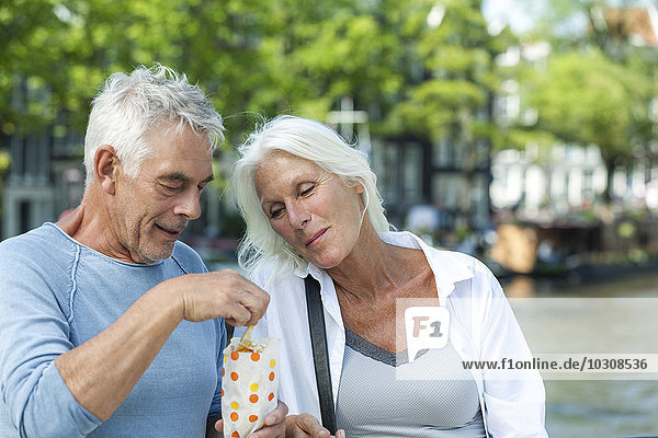 Netherlands  Amsterdam  senior couple eating French Fries