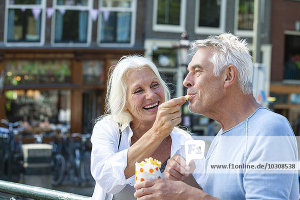 Netherlands  Amsterdam  happy senior couple eating French Fries