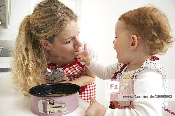 Mutter und kleine Tochter backen gemeinsam Kuchen in der Küche