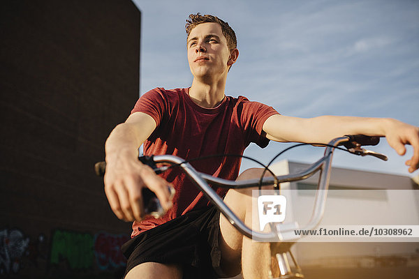 Junger Mann mit BMX-Fahrrad schaut weg