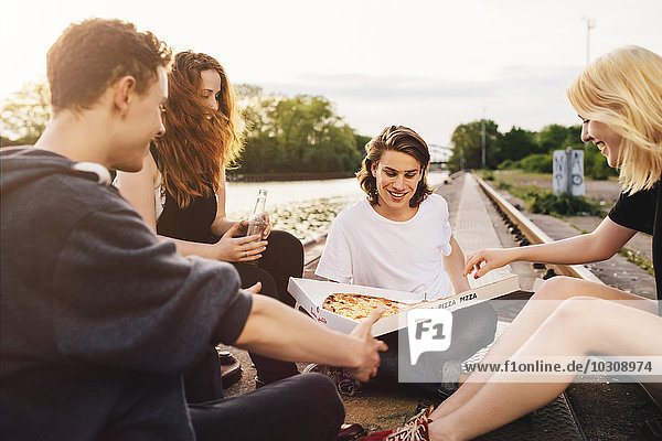 Friends sitting together outdoors sharing a pizza