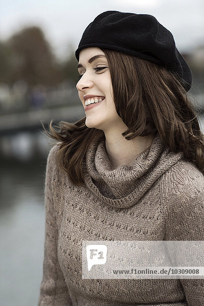 Porträt einer lächelnden jungen Frau mit Baskenmütze und Strickkleid
