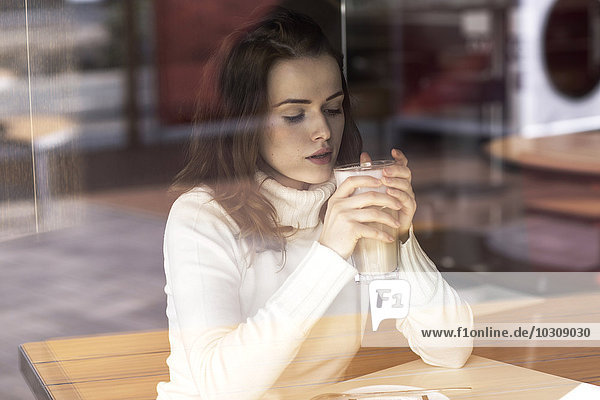Junge Frau mit Latte Macchiato sitzend in einem Café