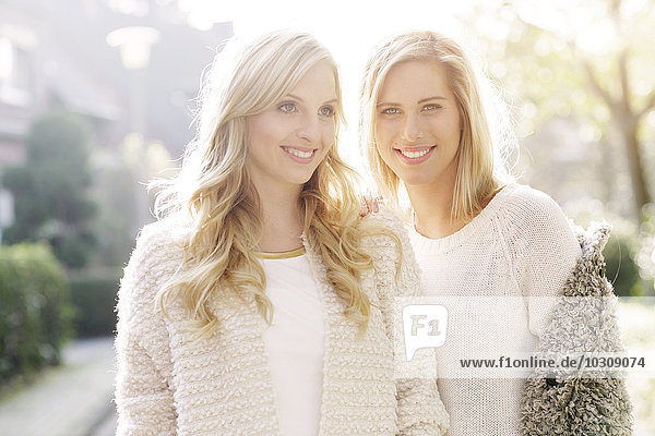 Portrait of two smiling blond women at backlight