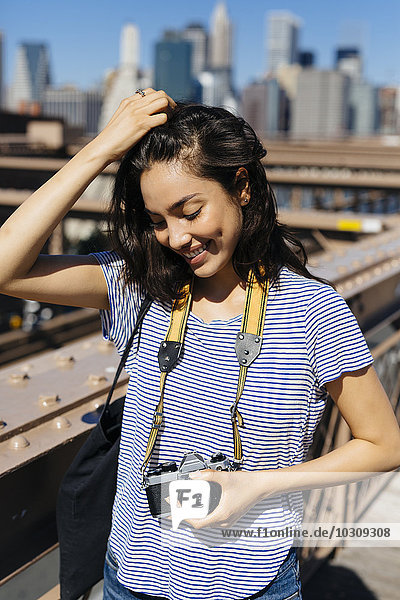 USA  New York City  Portrait einer lächelnden jungen Frau mit Kamera