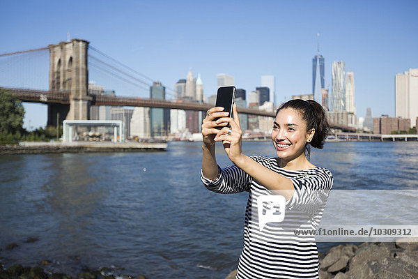 USA  New York City  young woman taking a selfie with smartphone