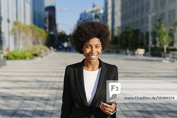 USA  New York City  portrait of smiling businesswoman with smartphone