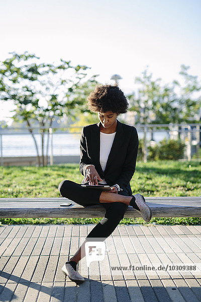 USA  New York City  Geschäftsfrau sitzend auf einer Bank mit digitalem Tablett
