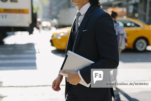 USA  New York City  businessman walking with digital tablet in Manhattan