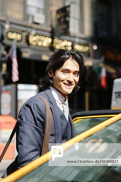 USA  New York City  lächelnder Geschäftsmann beim Einsteigen in ein Taxi
