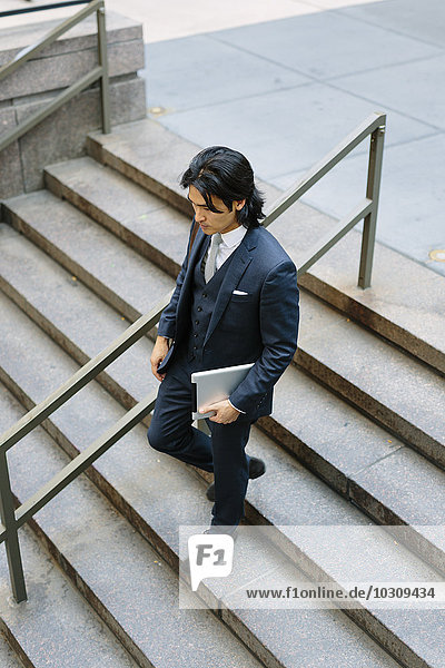 Businessman walking downstairs holding digital tablet
