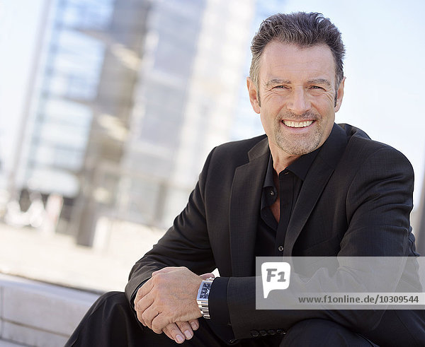 Portrait of smiling businessman wearing black suit
