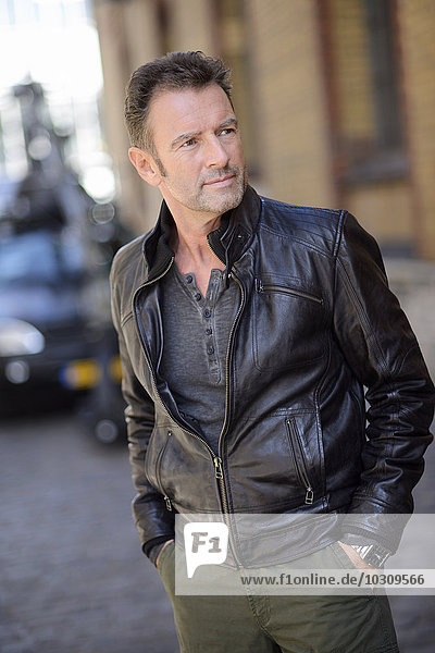 Portrait of man with hands in his pockets wearing black leather jacket