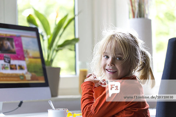 Porträt eines blonden kleinen Mädchens vor dem Computer