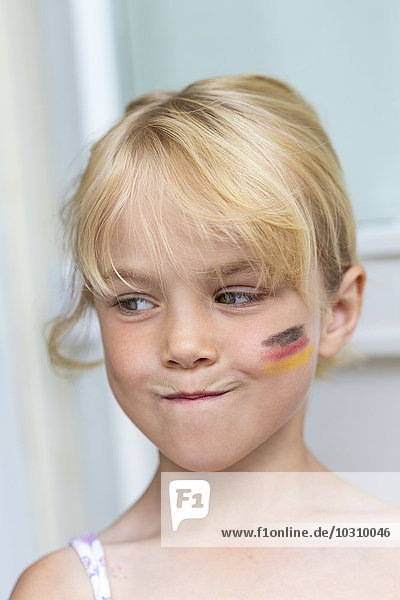 Porträt eines blonden Mädchens mit deutscher Flagge auf der Wange