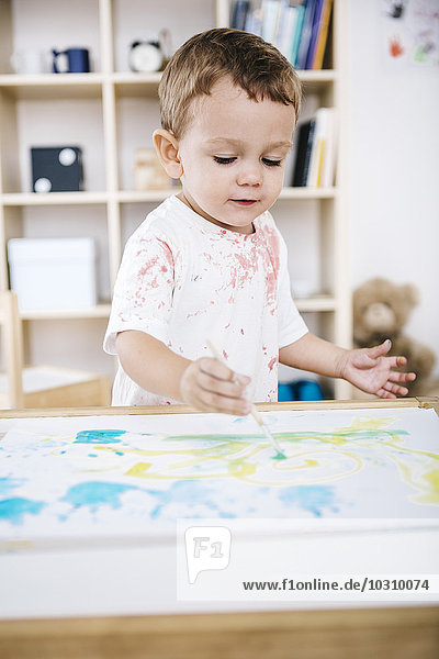 Portrait of little boy painting with watercolours