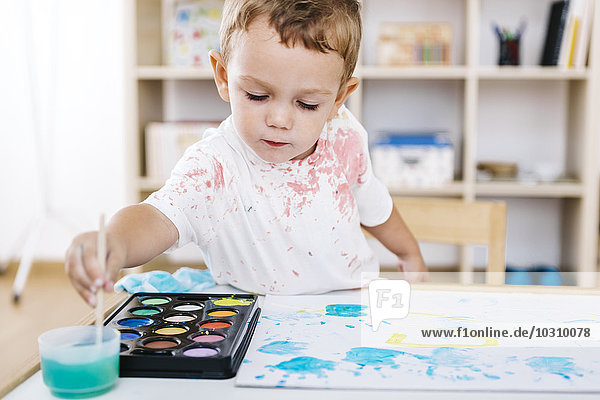 Portrait of little boy painting with watercolours