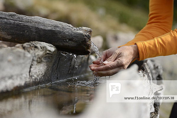 Hands scooping water from a well