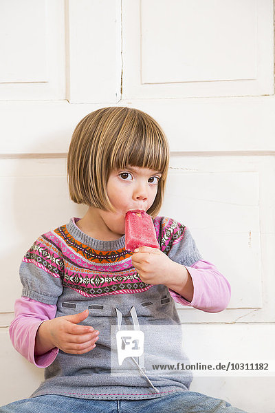 Portrait of little girl eating raspberry ice lolly