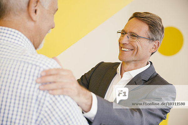 Portrait of smiling mature man talking to another man in an office