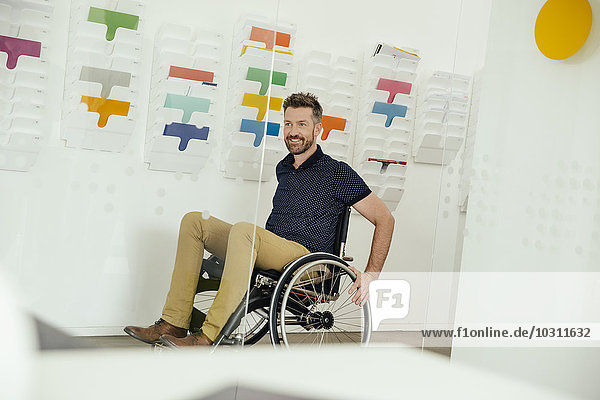 Lächelnder Mann im Rollstuhl im modernen Büro
