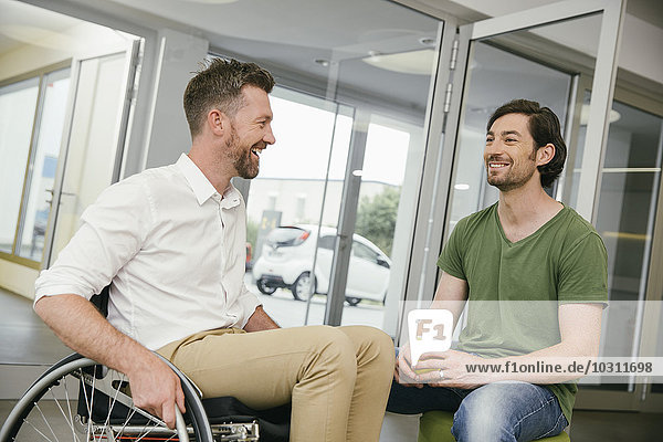 Mann im Rollstuhl im Gespräch mit Kollegen