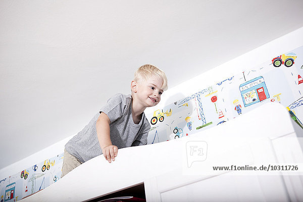 Kleiner Junge klettert auf Garderobe im Kinderzimmer