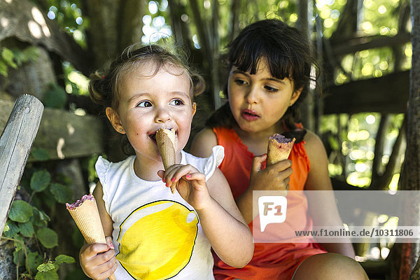 Two little sisters eating ice cream