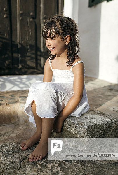 Spain  Balearic Islands  Menorca  Binibeca  portrait of little girl sitting on a step