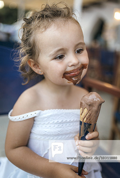 Porträt eines lächelnden kleinen Mädchens mit Schokoladeneis um den Mund herum